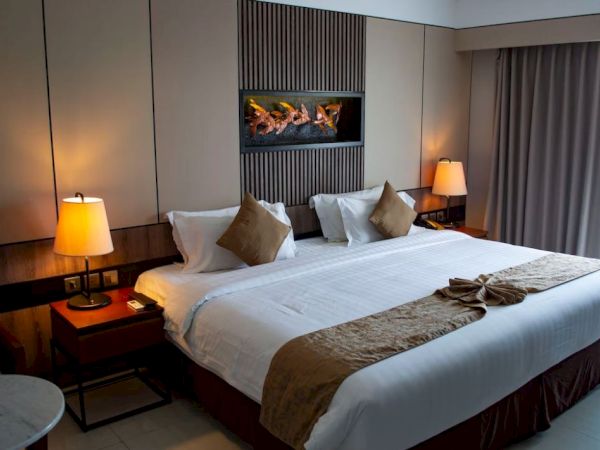 A cozy hotel room with a large bed, warm lighting from two lamps, and a decorative feature above the headboard.