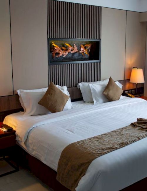 A cozy hotel room with a large bed, decorative pillows, two bedside tables with lamps, and artwork above the bed.