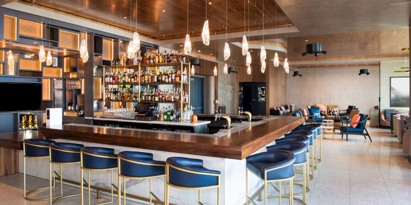 A stylish bar with modern seating, a well-stocked liquor display, and warm lighting in a spacious lounge area, offering a relaxed vibe.